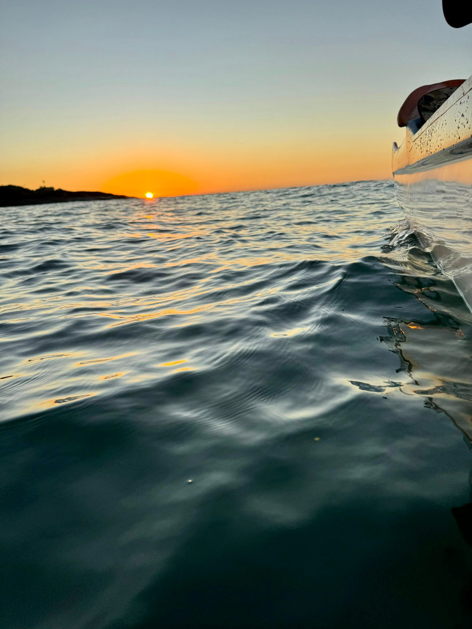 Detalhe da água e canoa ao pôr do sol